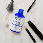 Eyelash serum bottle with applicator, pencil, and mascara on a marble surface