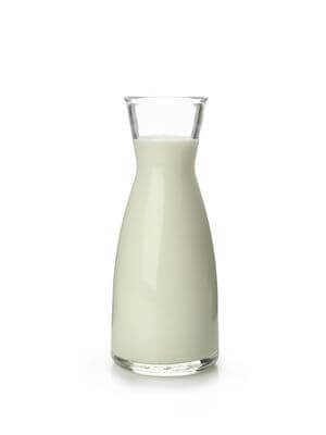 Clear glass bottle filled with creamy goat milk